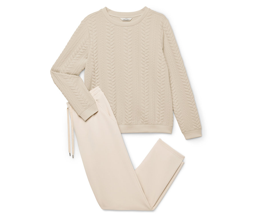 Béžová domácí souprava sestávající ze svetru s copánkovým vzorem a kalhot se stahovací šňůrkou.