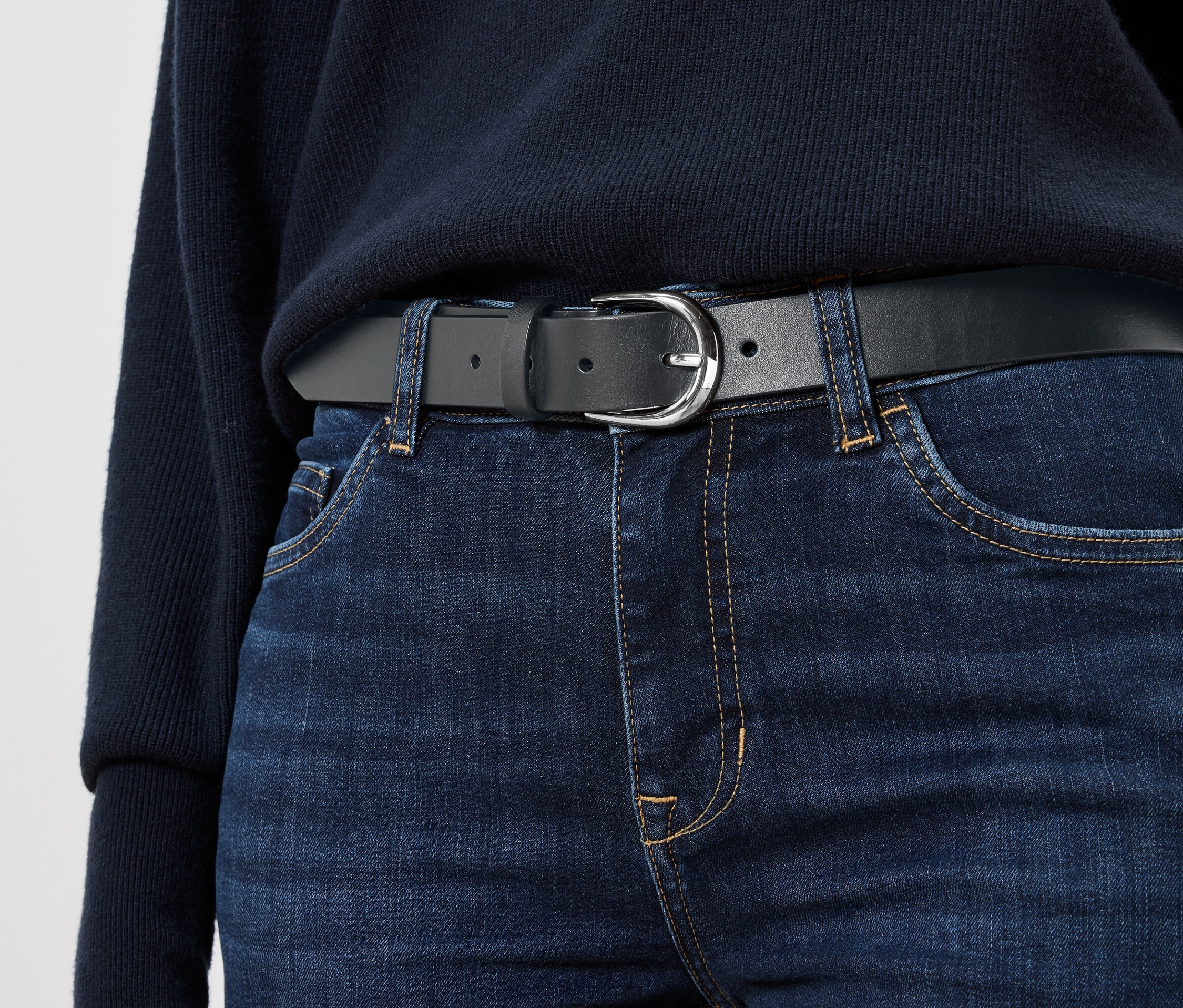 Černé kožené opasek na modrých džínách.