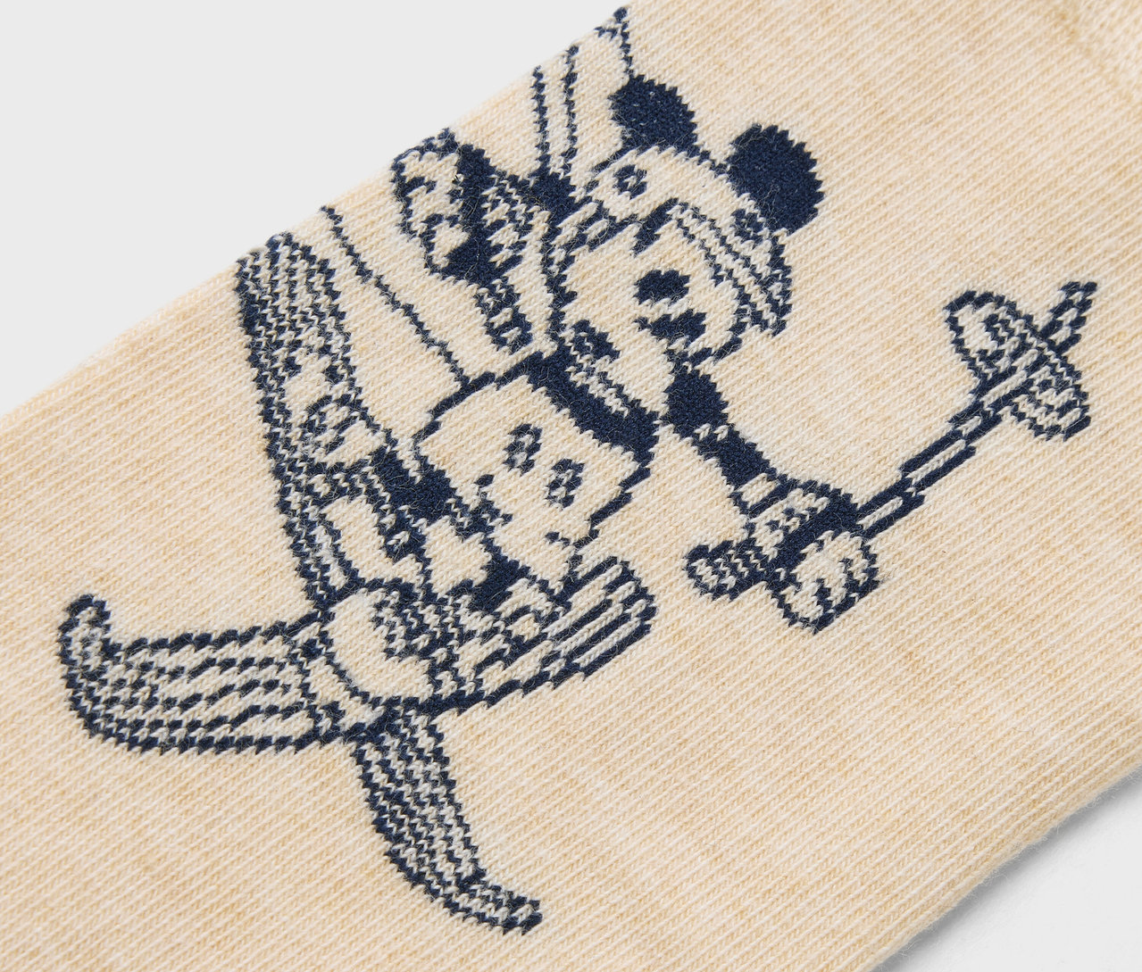 Detail béžové ponožky s tmavě modrým vzorem Mickeyho Mouse na lyžích.