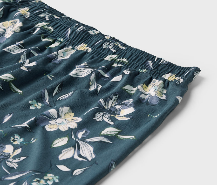 Detailně zobrazený elastický pas a látka s květinovým vzorem na kalhotách.
