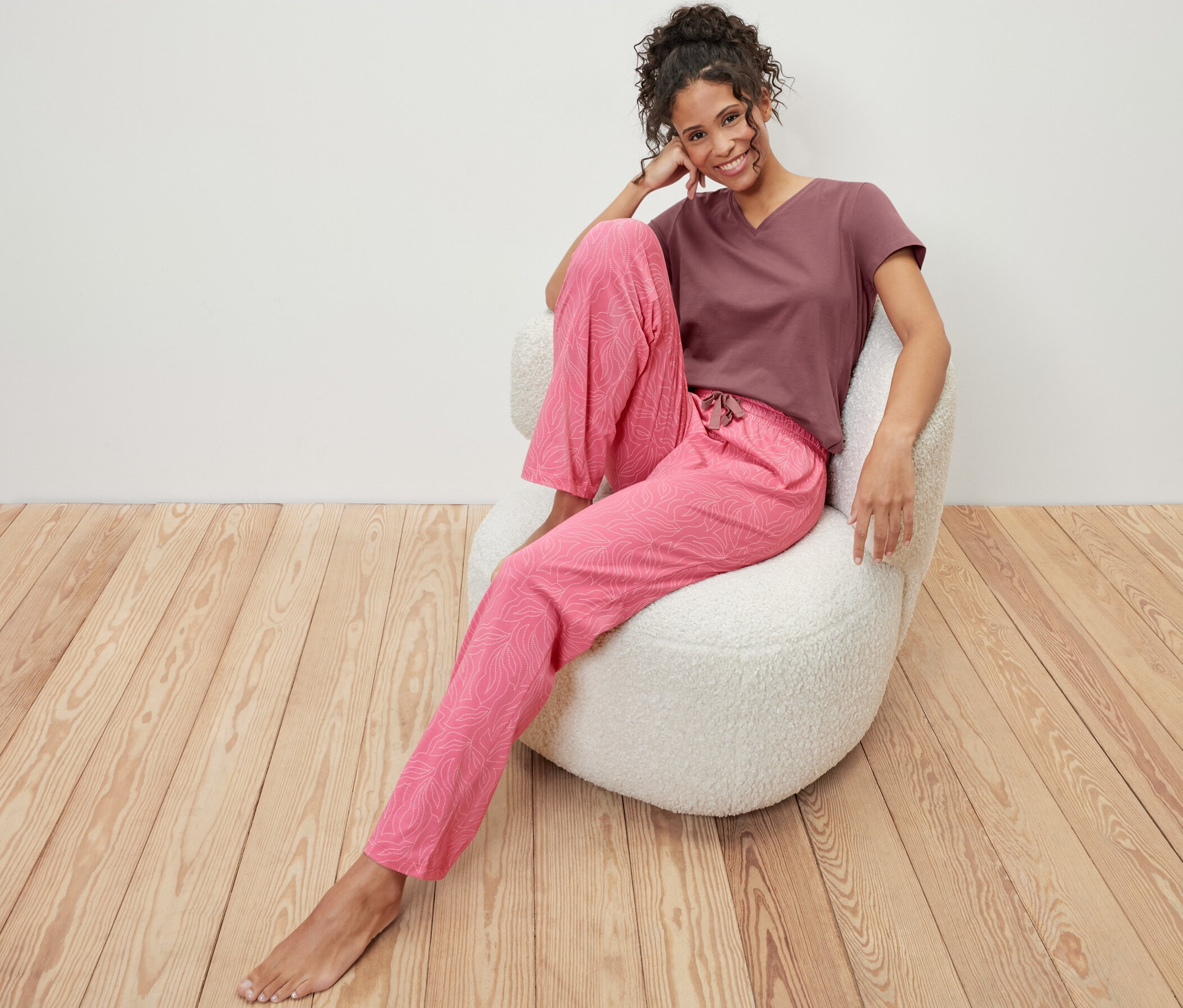 Žena sedí v křesle a má na sobě pyžamo.