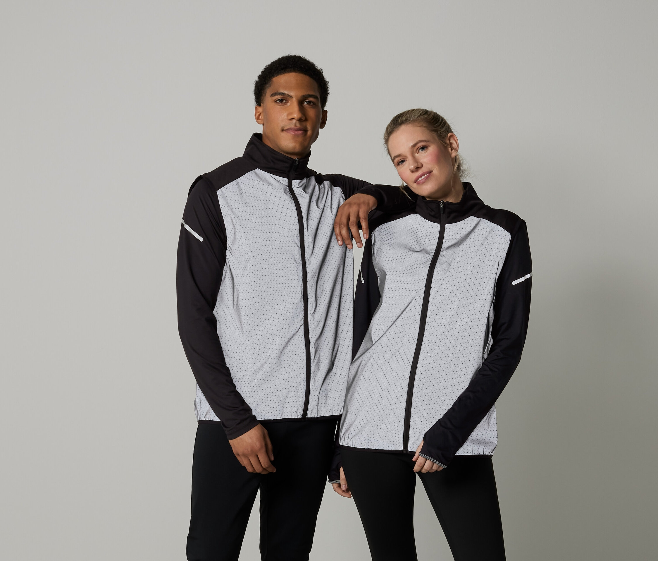 Muž a žena pózují v bundách s dlouhým rukávem a zipem.