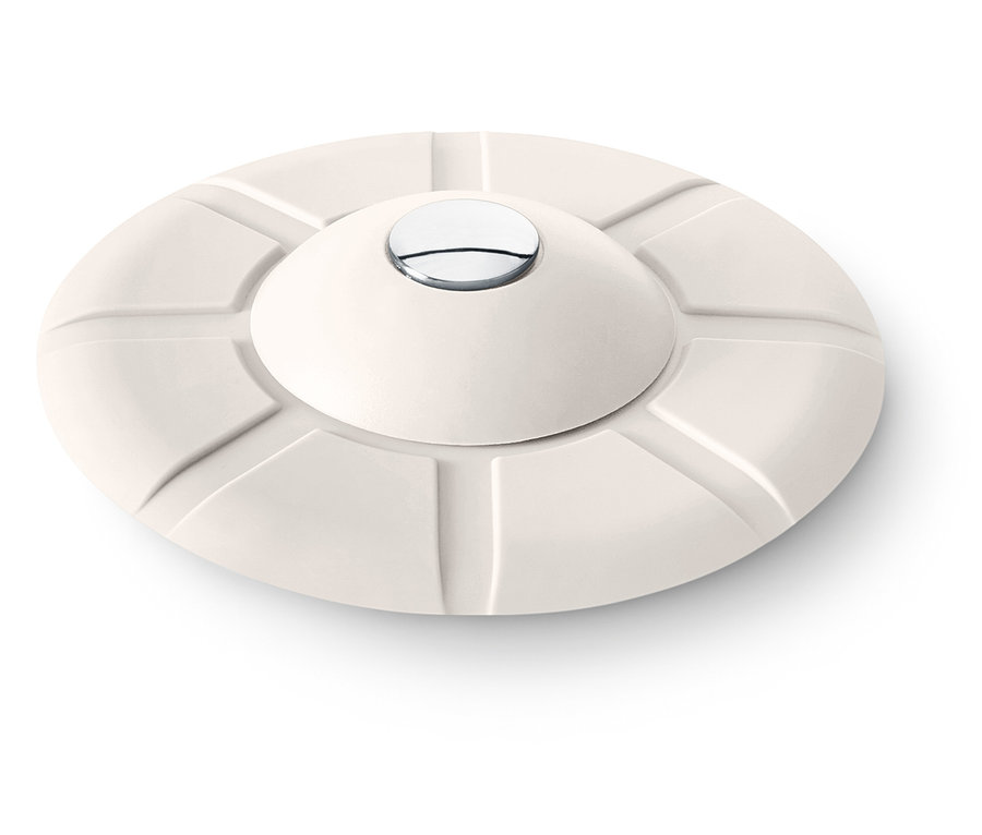 Krémový kulatý předmět s konvexním vrcholem a stříbrným knoflíkem uprostřed.