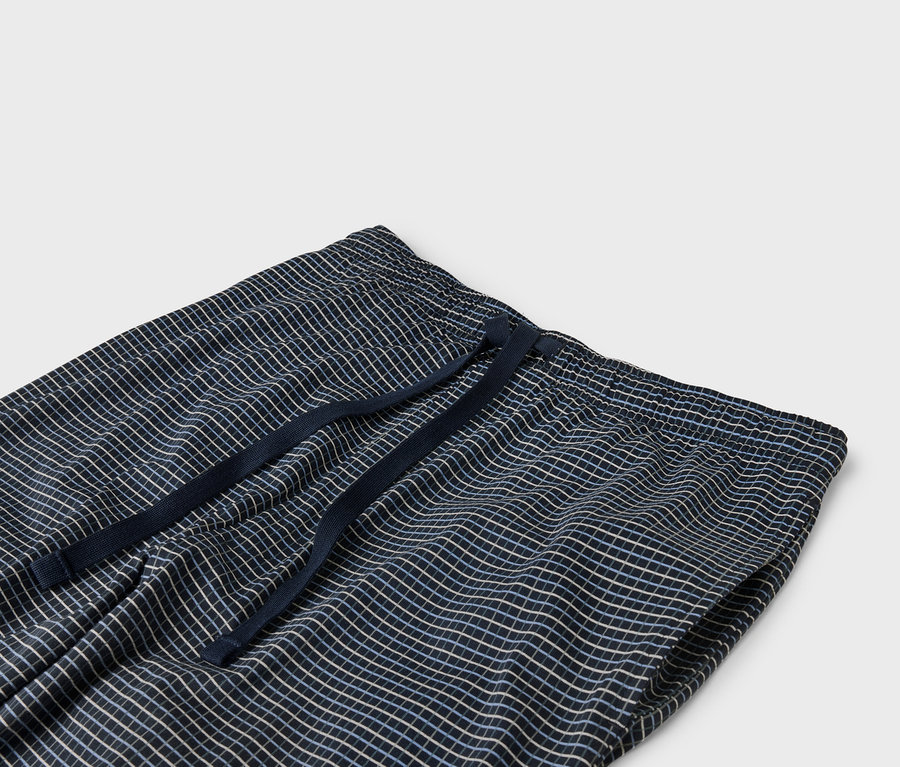 Detail modrých kostkovaných kalhot s elastickým pasem se stahovací šňůrkou.