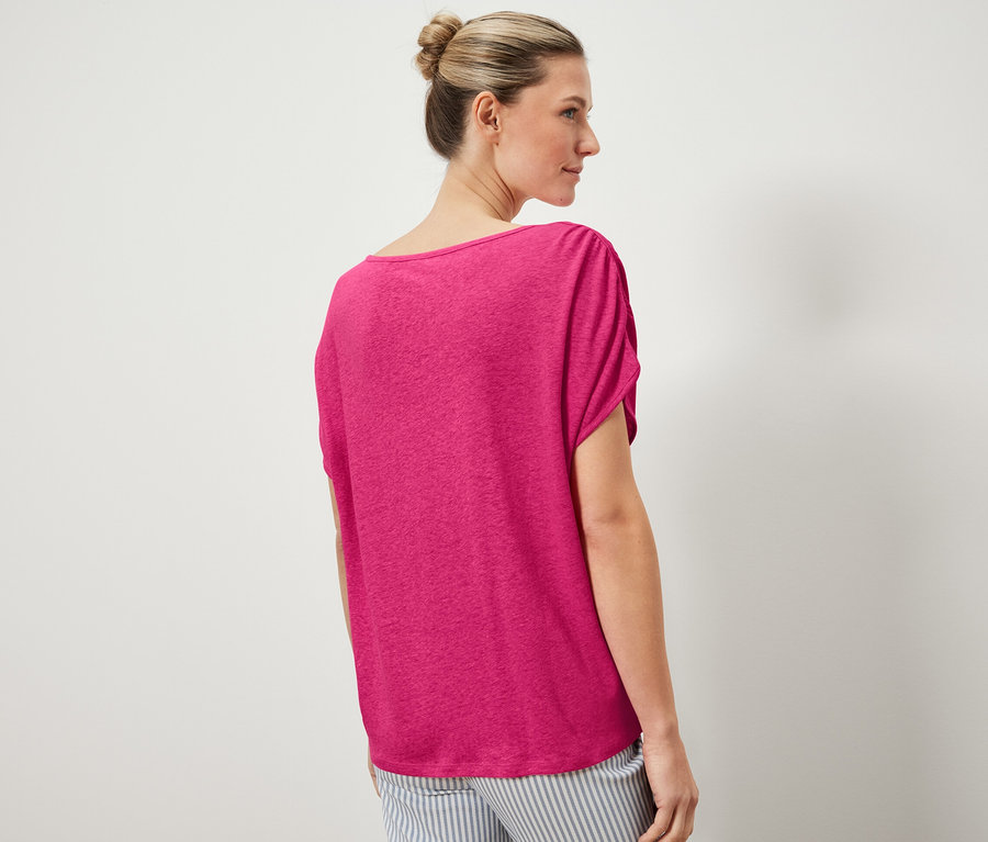 Žena má na sobě tričko ze směsi lnu a pruhované kalhoty.