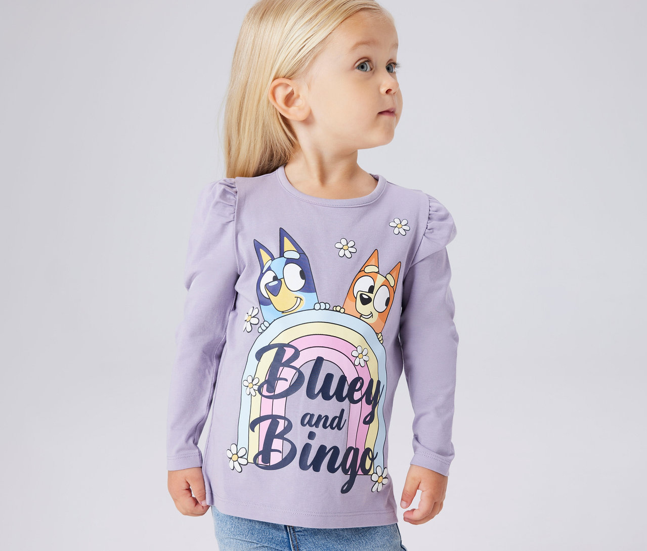 Dívka má na sobě dětské triko s dlouhým rukávem NAME IT »BLUEY« s potiskem Bluey a Bingo.