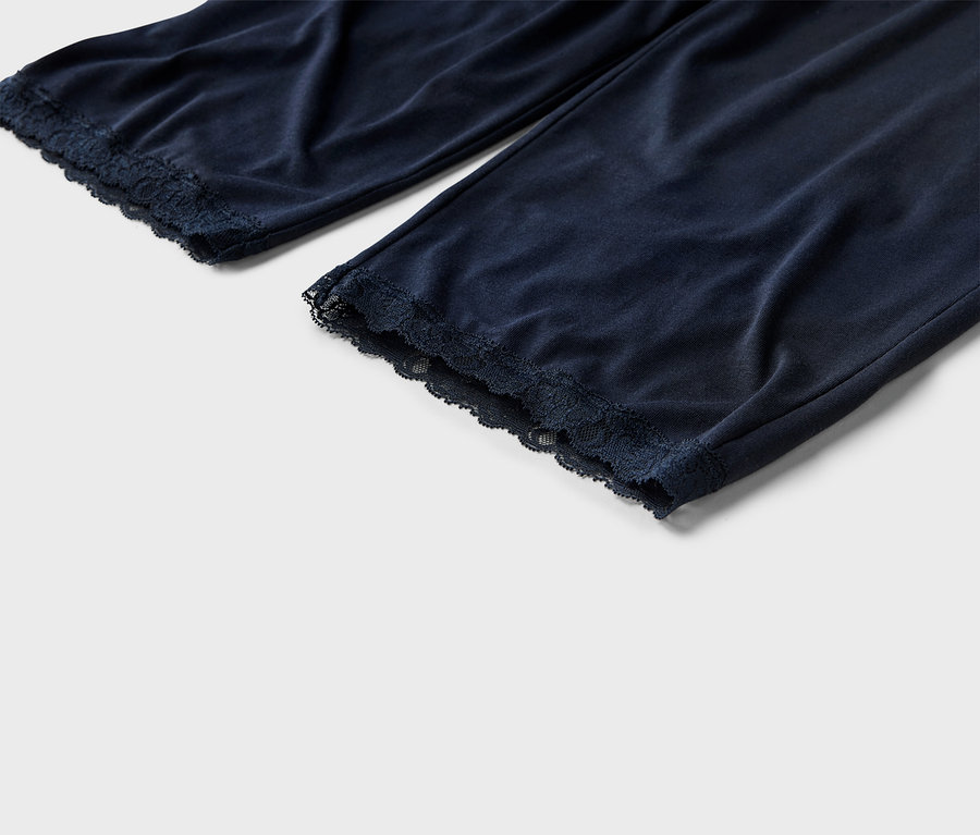 Detailní záběr na tmavě modré pyžamové kalhoty s krajkovým lemem