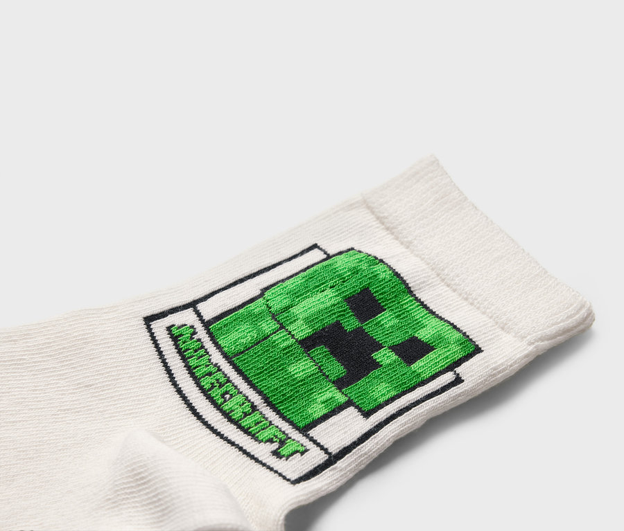 Detail bílé ponožky se zeleným motivem Minecraft Creeper.