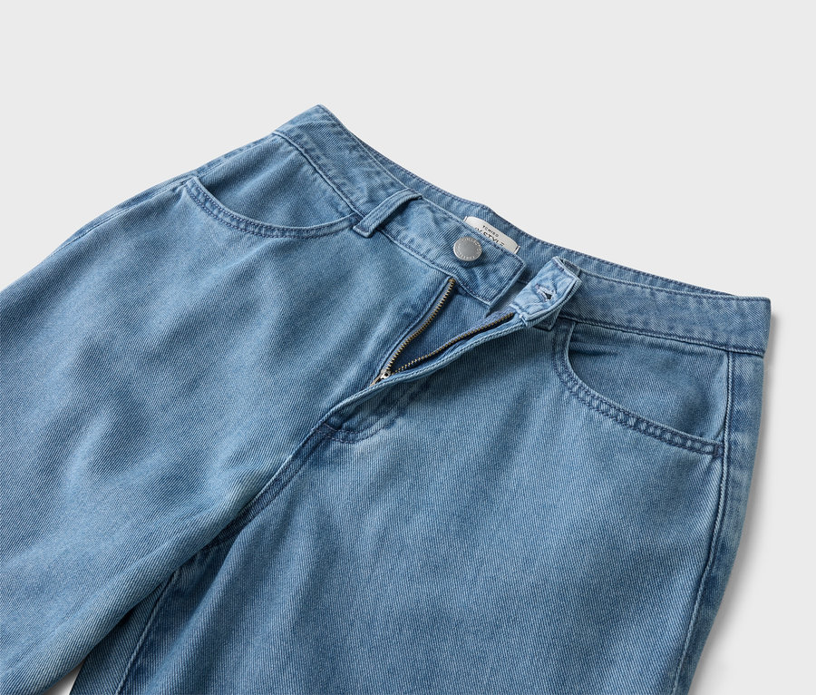 Detailní záběr světle modrých džínů s rozepnutým zipem.