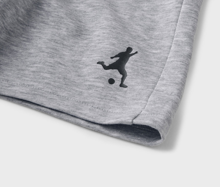 Detail šedých šortek s černou siluetou fotbalisty.