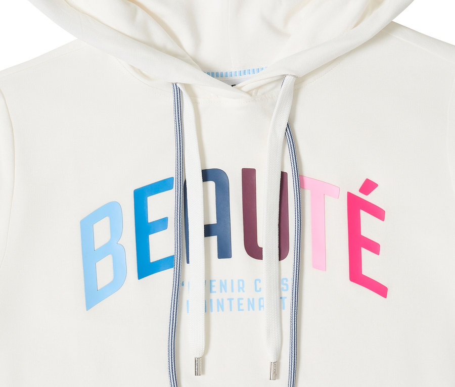Detail bílého trička s kapucí CECIL se stahovací šňůrkou. Je potištěno barevným nápisem „Beauté“.
