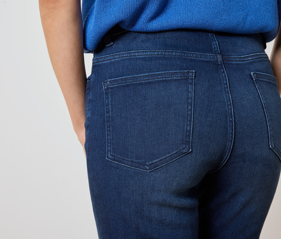 Detailní záběr na záda ženy v tmavě modrých džínách a modré halence.