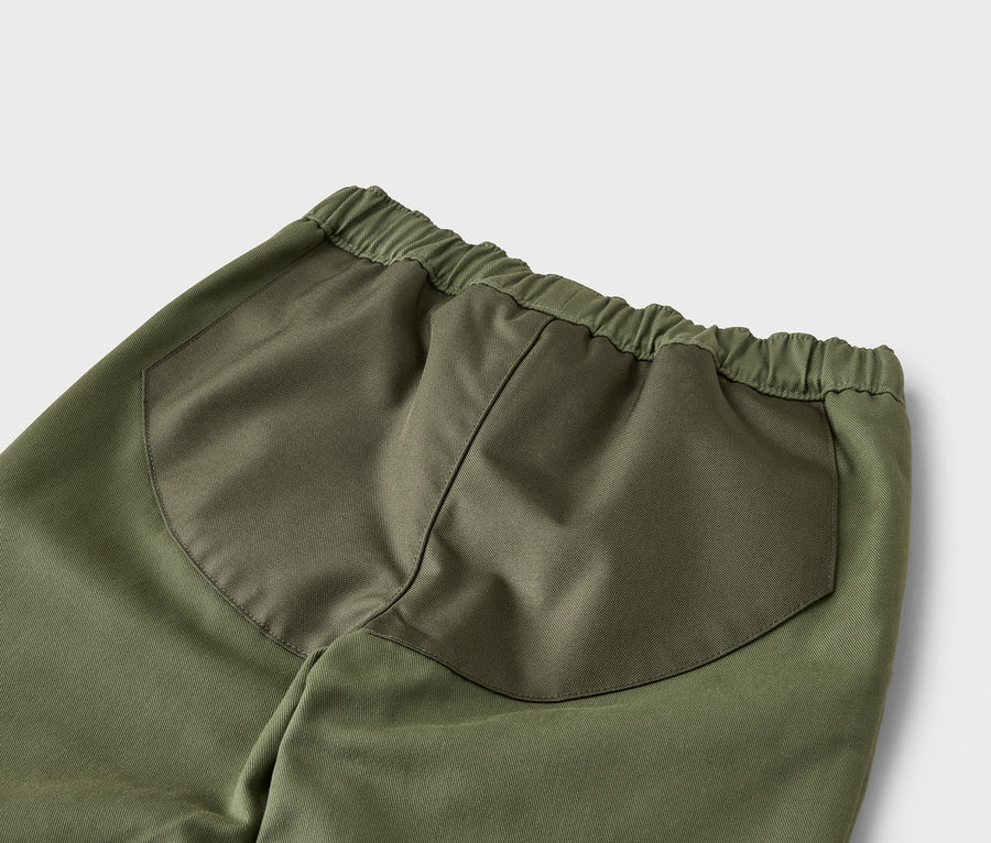 Detailní záběr na zadní část zelených kalhot s elastickým pasem a našitými kapsami.