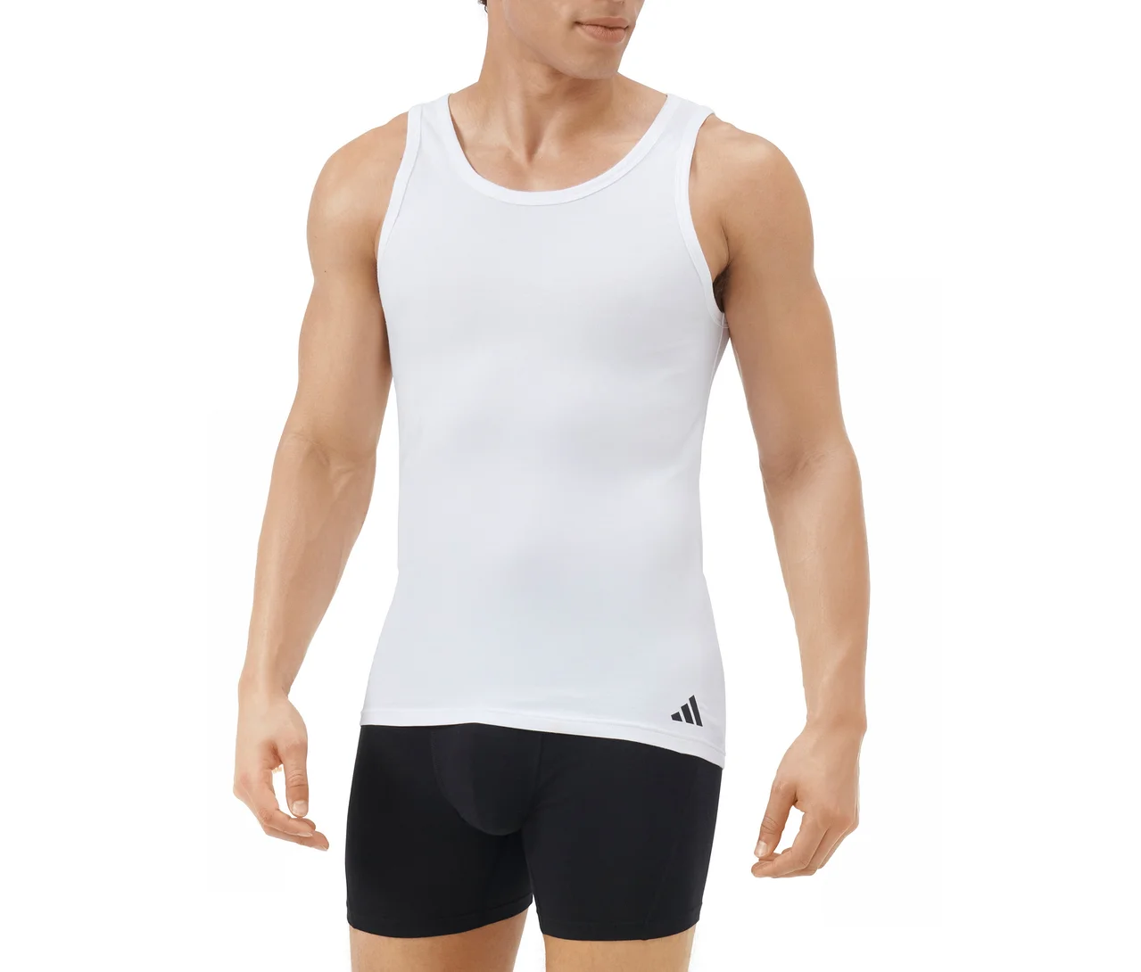 Muž v bílém tílku s černým logem Adidas na levém lemu a černých boxerkách, na bílém pozadí.