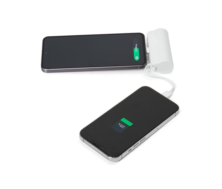 Dva smartphony, jeden z nich připojený k bílé přenosné nabíječce, leží na bílém povrchu.