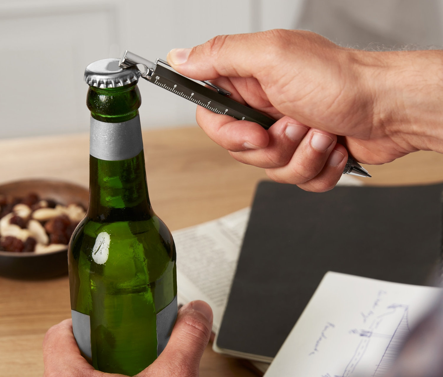 Muž otevírá zelenou láhev multifunkční propiskou.