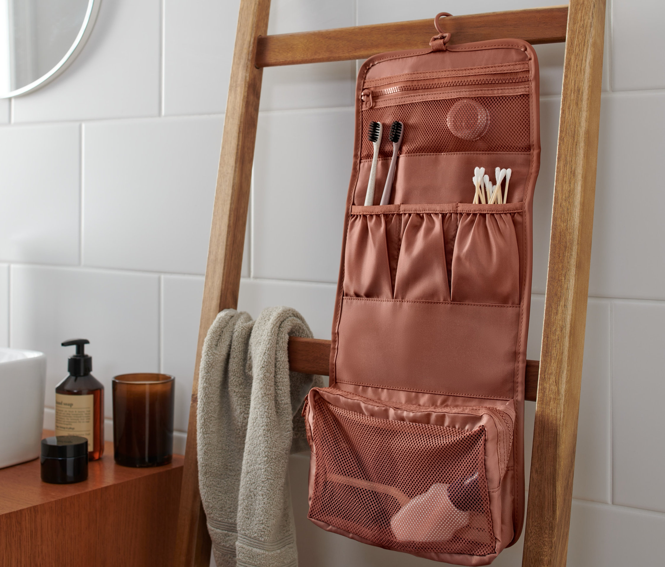 Rozložená toaletní taštička visí na žebříku v koupelně.