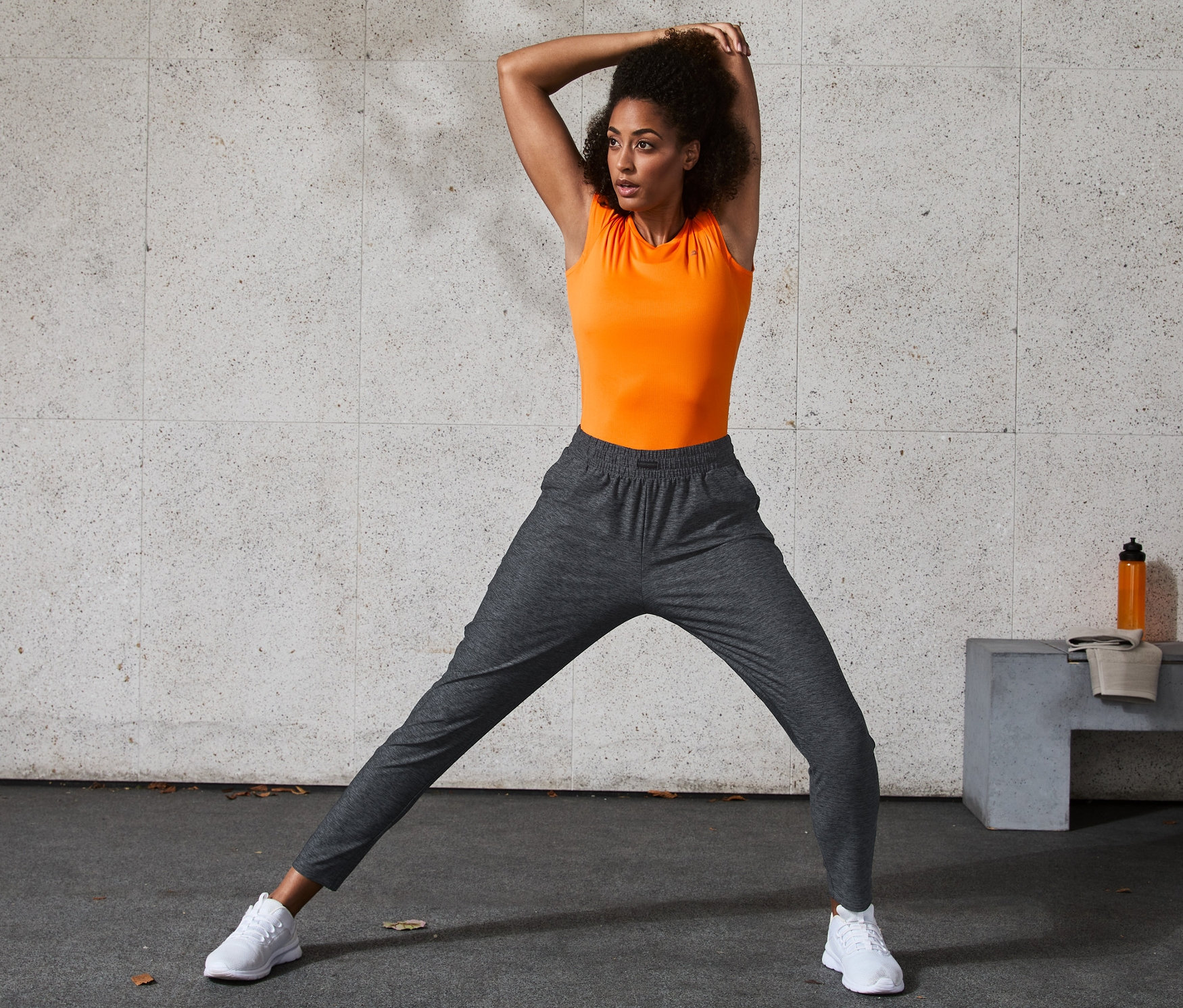 Žena protahuje nohy ve sportovních kalhotách.