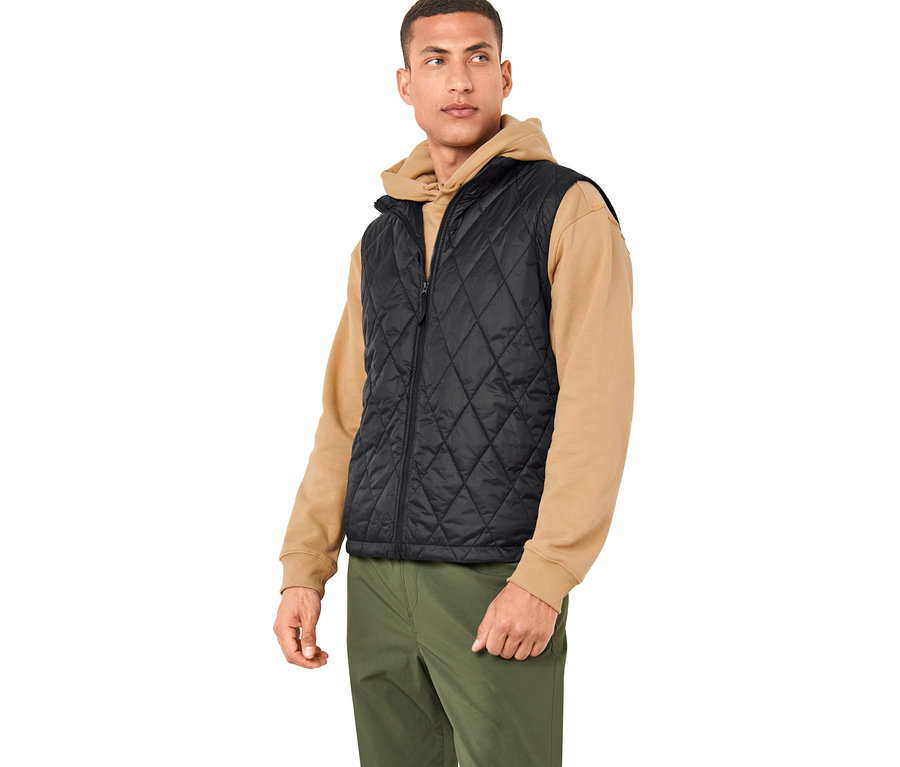 Muž má na sobě černou vestu z outdoorové bundy 3 v 1 a olivově zelené kalhoty.