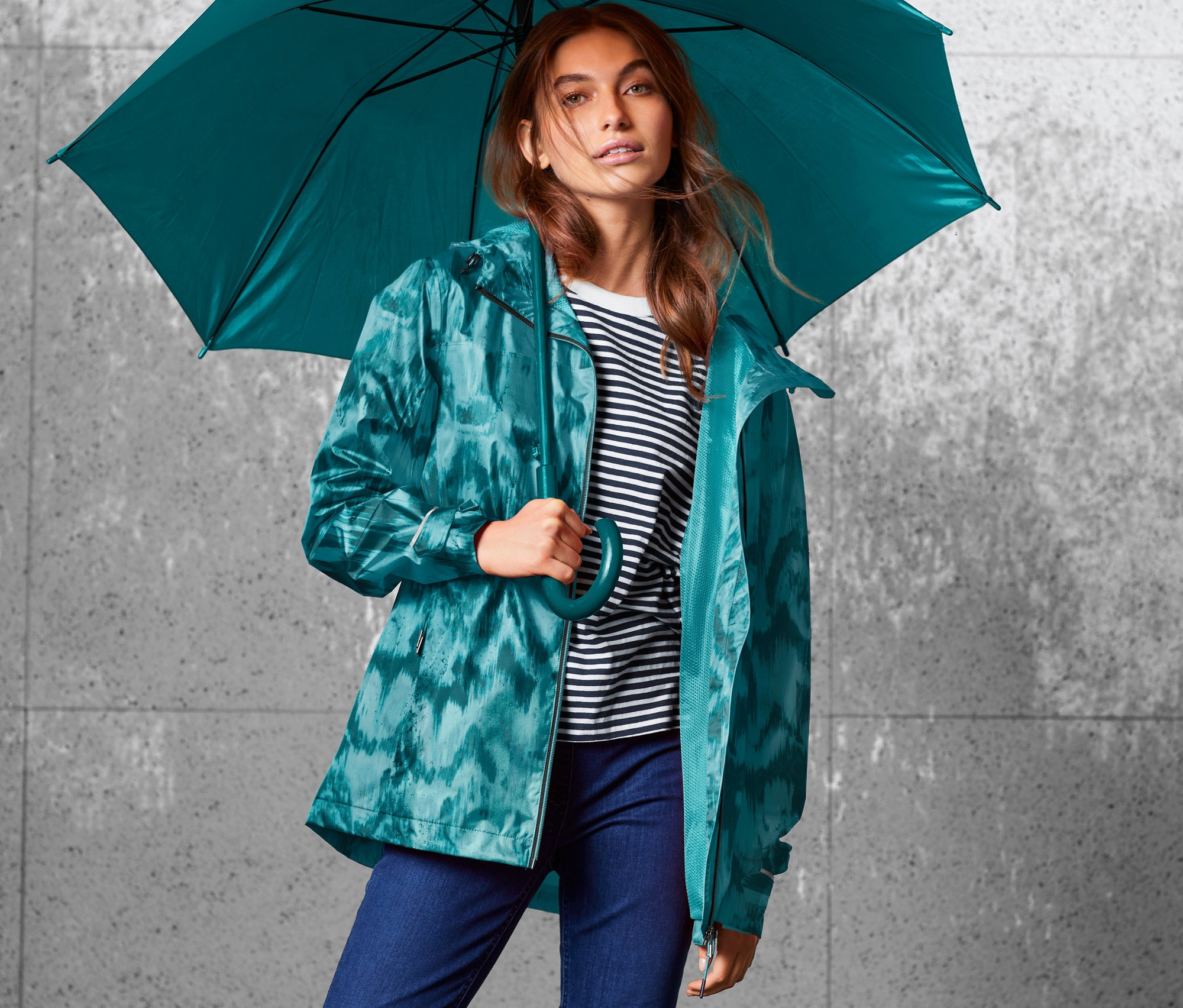Žena drží deštník a má na sobě bundu do deště s celoplošným potiskem.