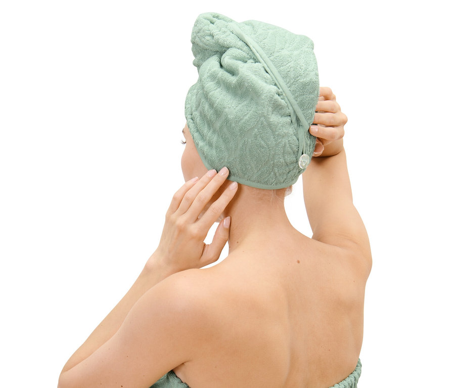 Žena si upravuje ručníkový turban na hlavě.