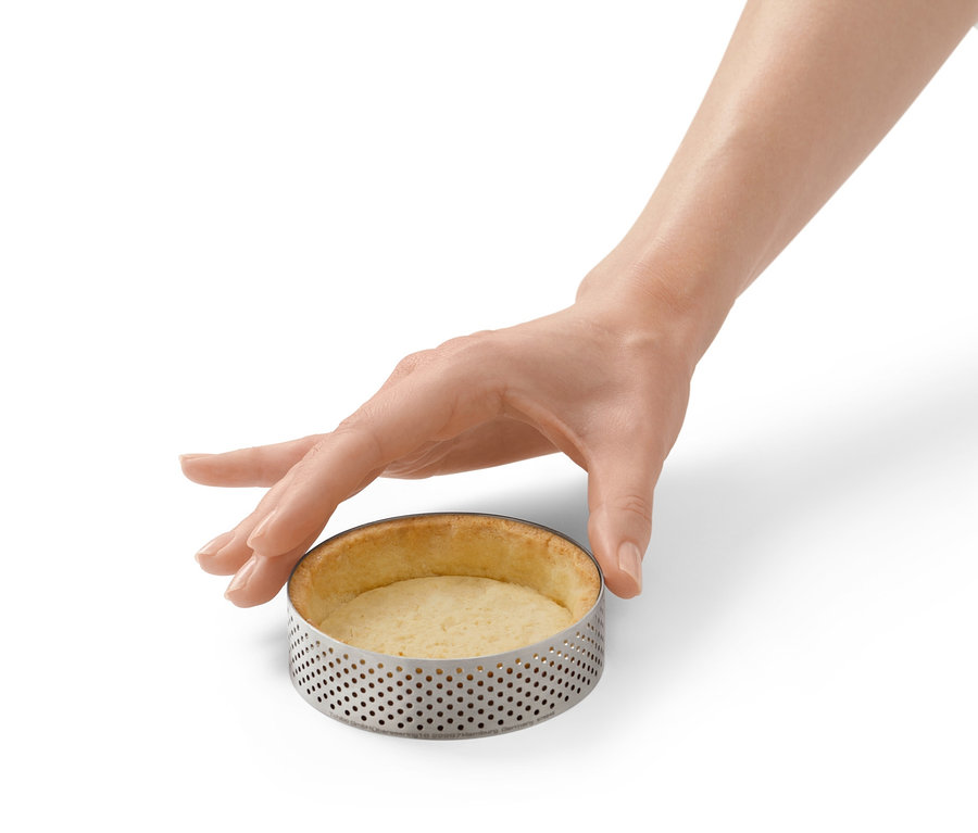 Ruka se dotýká pečicího ráfku z ušlechtilé oceli se zapečeným těstem.