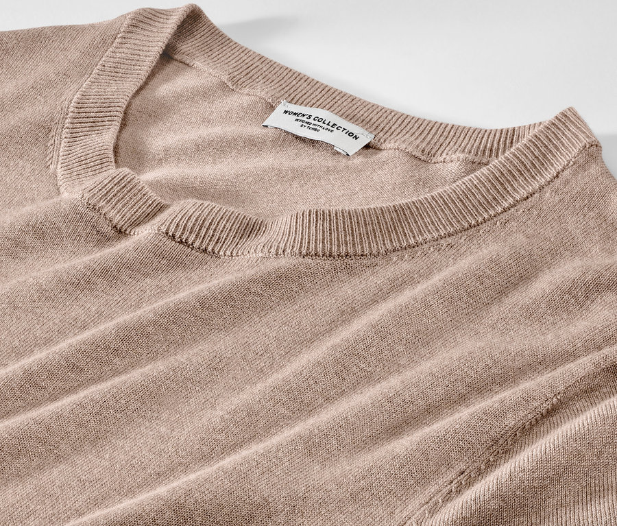 Detail světle hnědých šatů z jemného úpletu.