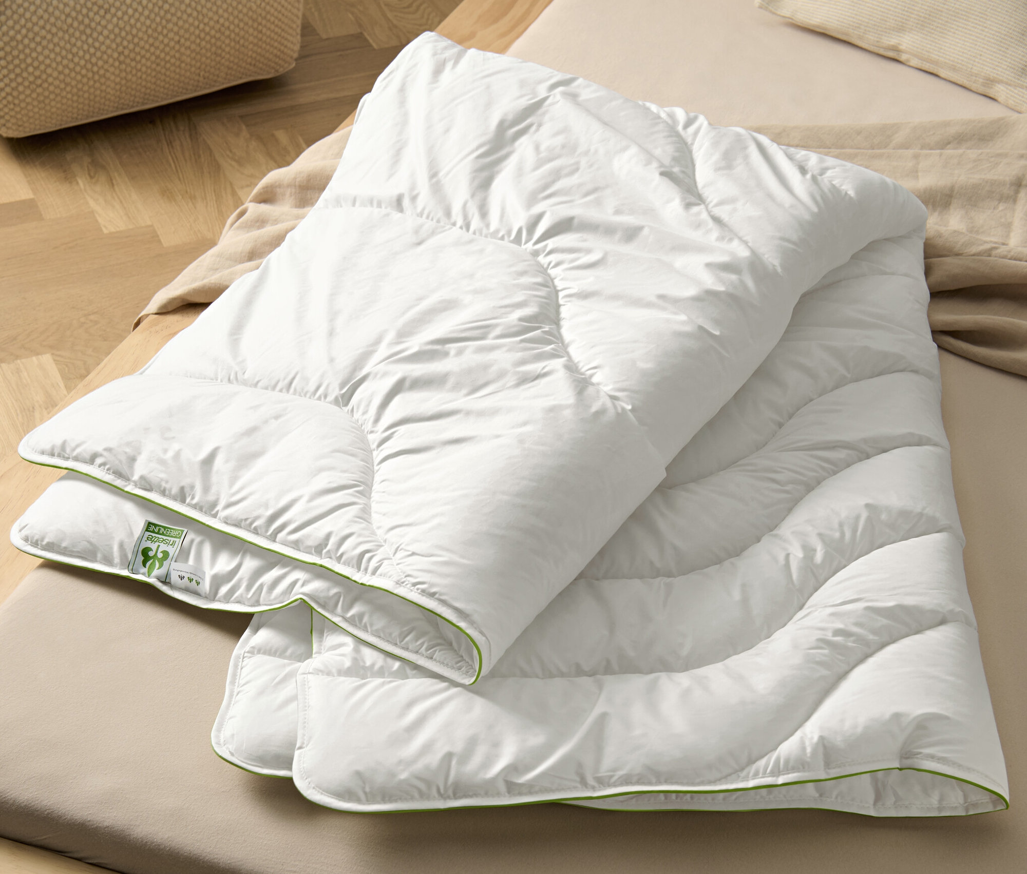 Na posteli leží bílá prošívaná přikrývka irisette® greenline Megafil® BIO.