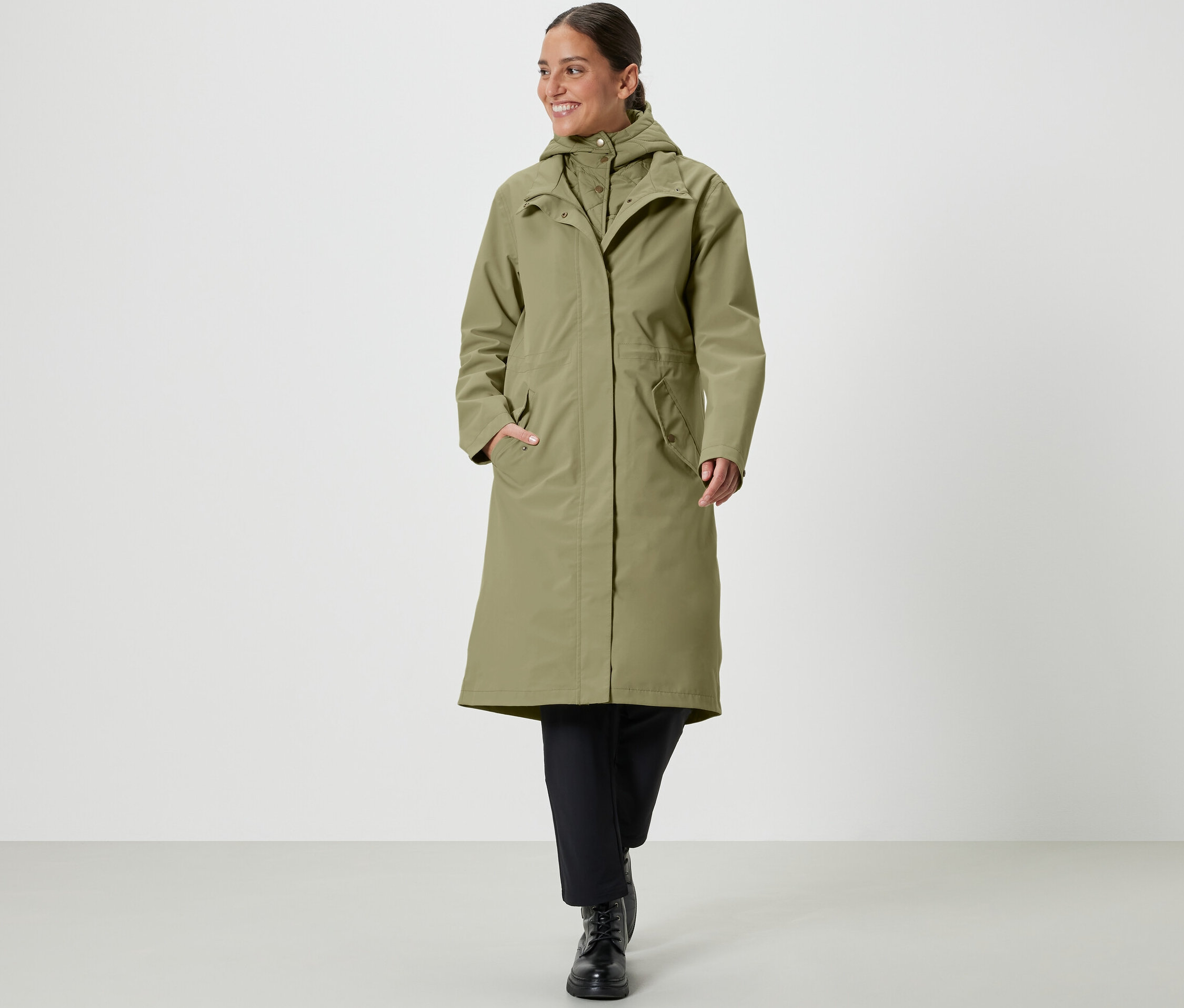 Žena kráčí a má na sobě khaki kabát do deště.