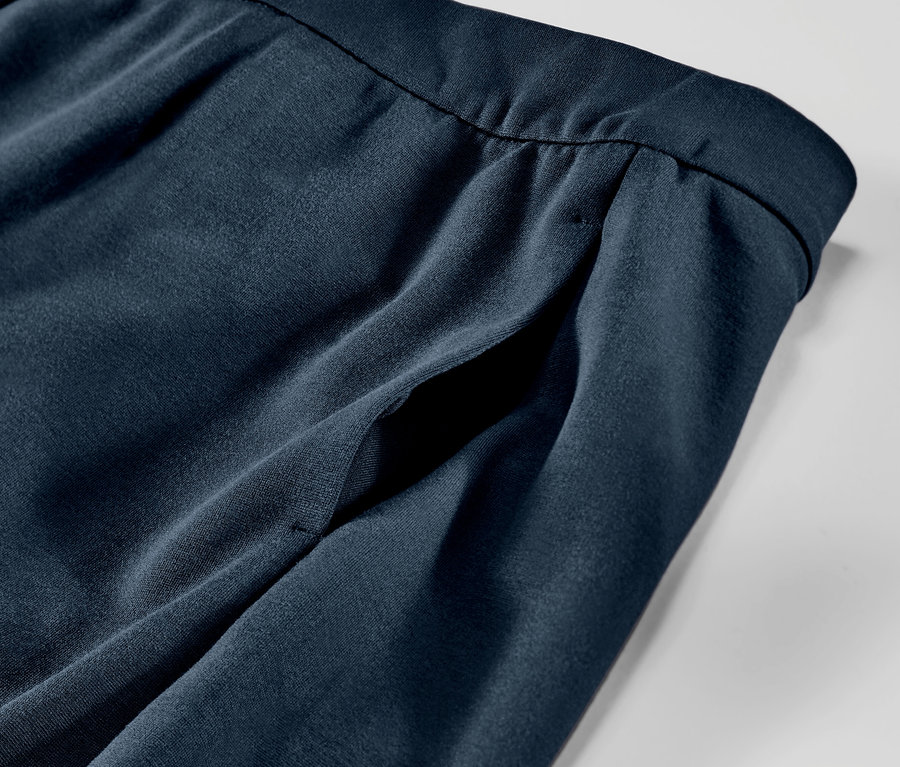 Detailní pohled na tmavě modré jersey kalhoty s kapsou a prošitím.