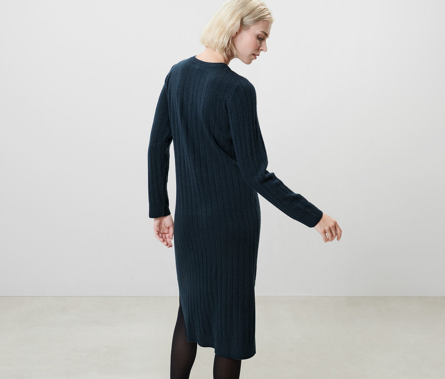 Blondýna pózuje v tmavě modrých žebrovaných pletených šatech.