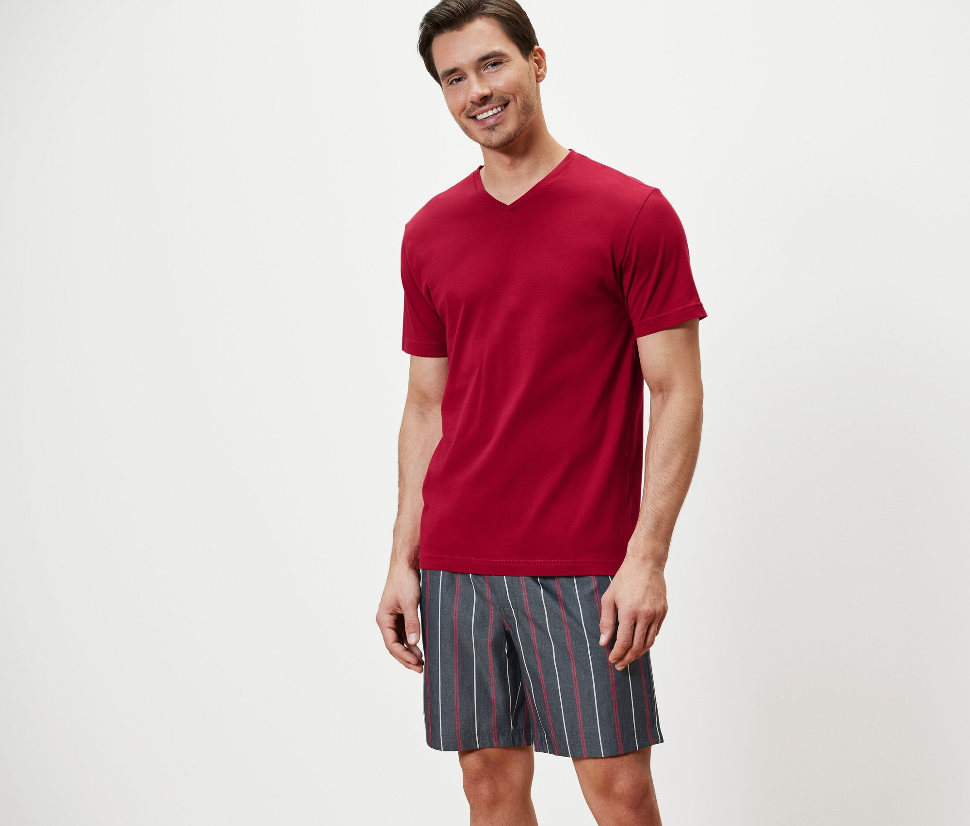 Muž má na sobě krátké pyžamo a usmívá se.