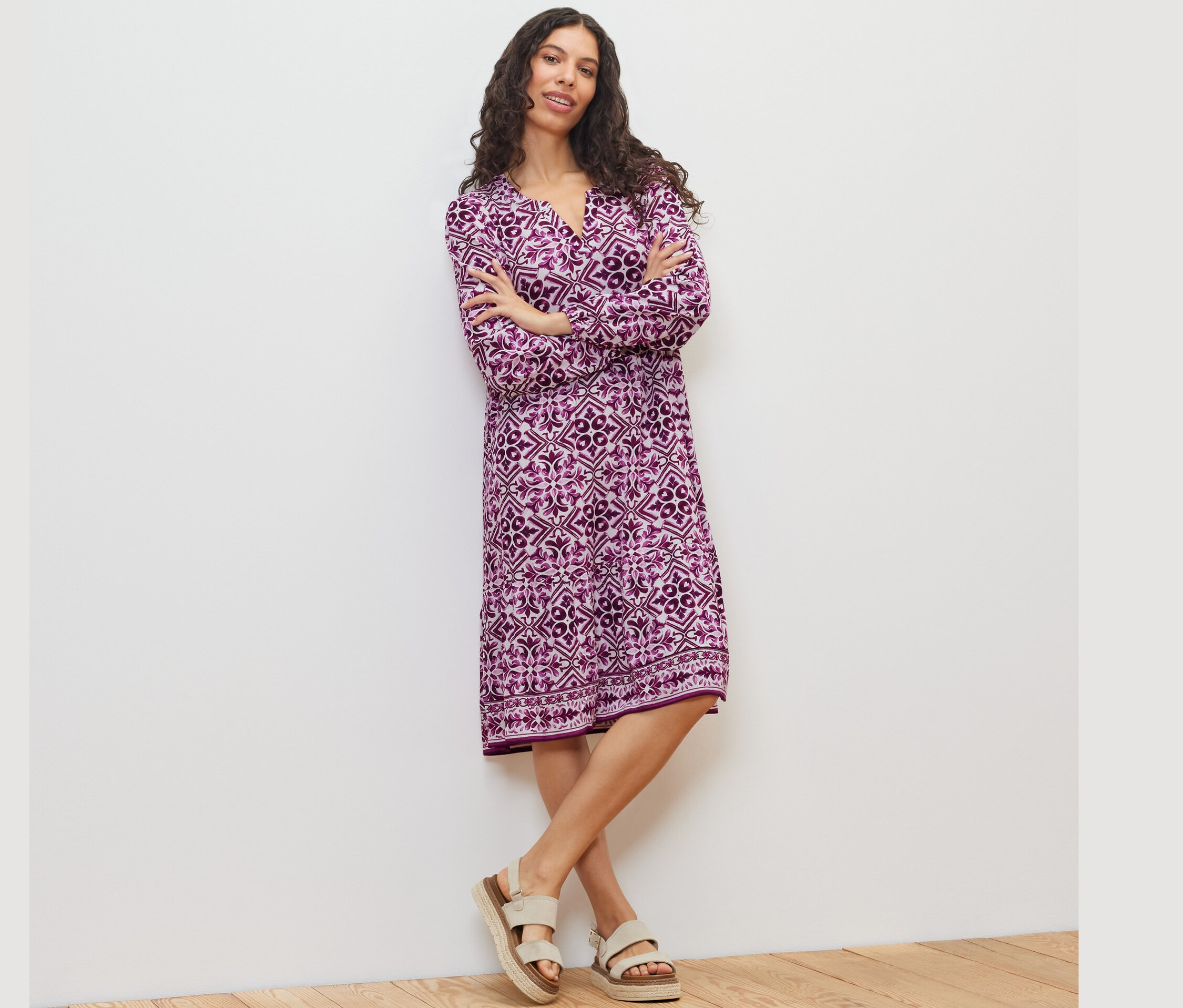 Žena pózuje v tkaných šatech s potiskem.