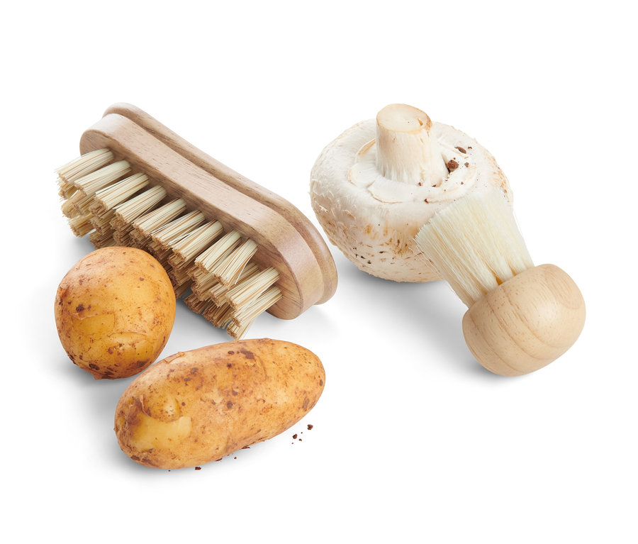 Dva brambory a žampion vedle dvou kartáčků na zeleninu.