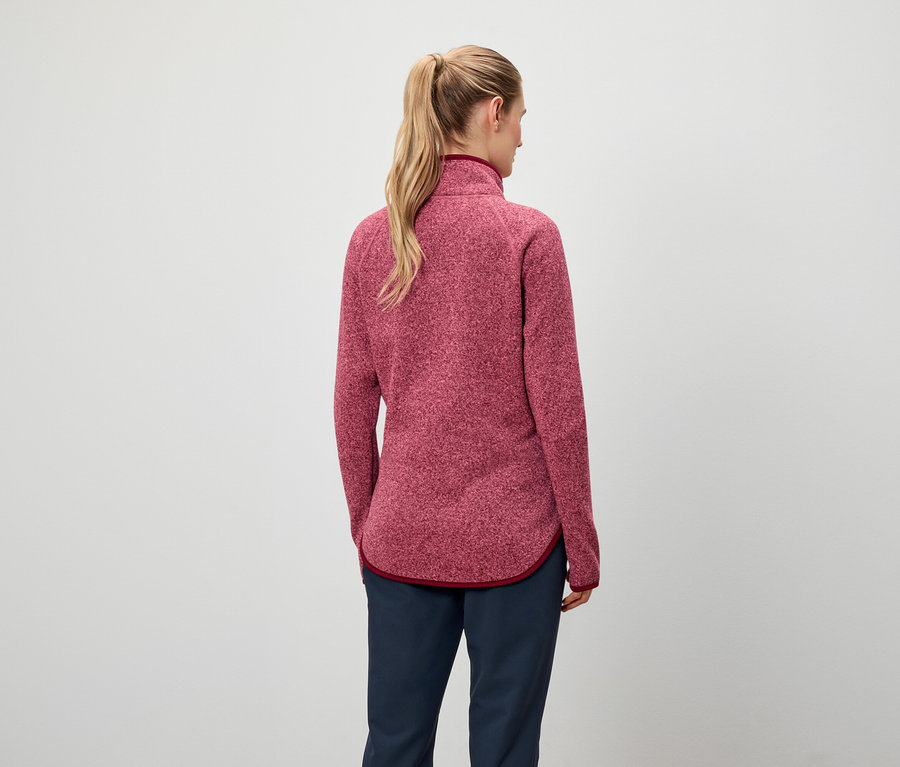 Zezadu je vidět žena s blond vlasy staženými do culíku, má na sobě červenou mikinu a tmavě modré kalhoty.