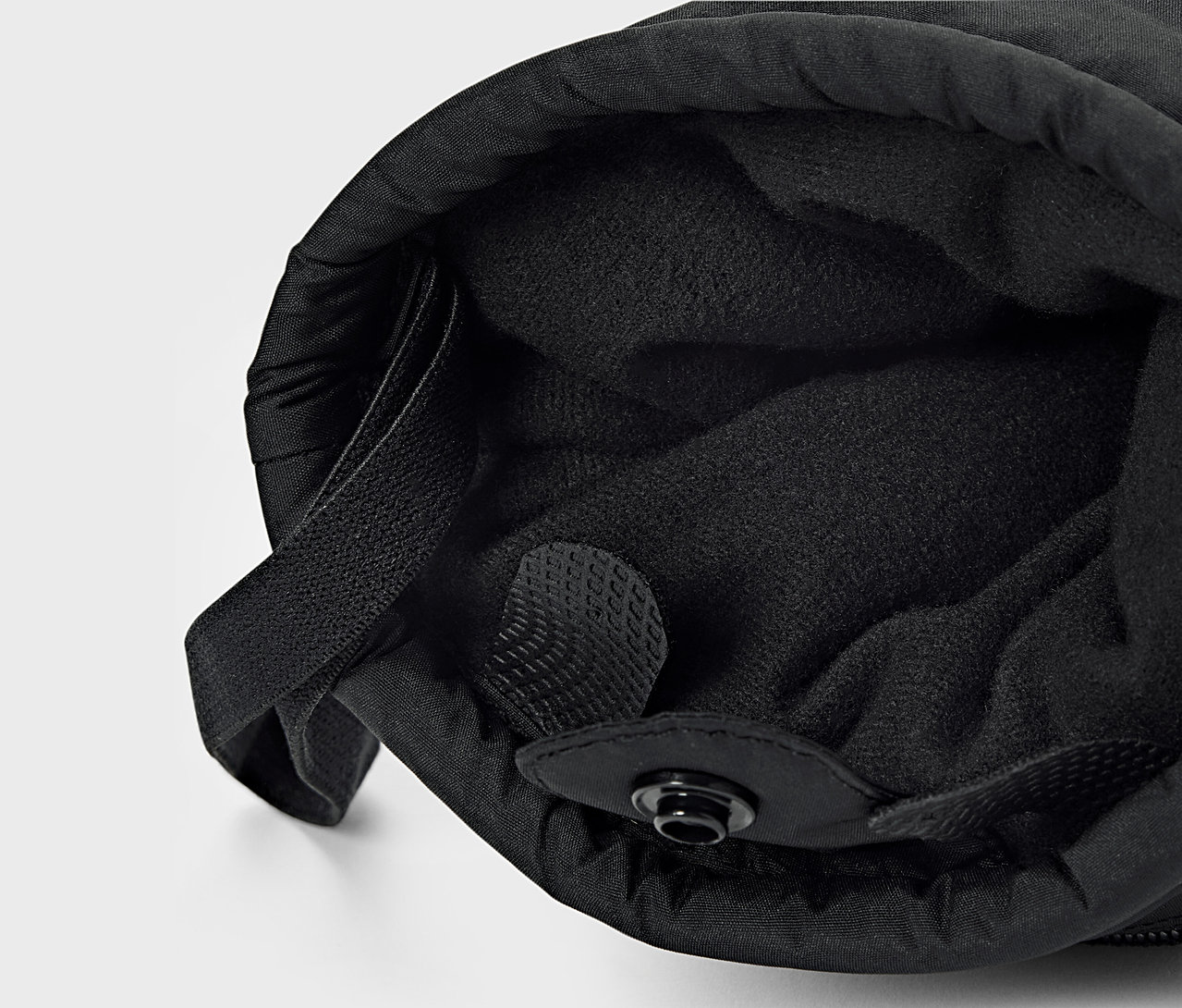 Detail černé látky s vnitřní podšívkou a stahovací šňůrkou.