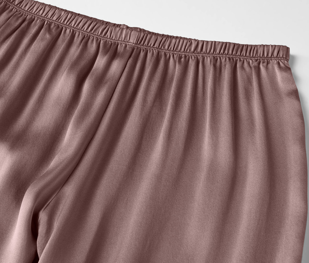 Detail fialových saténových kalhot s elastickým pasem.