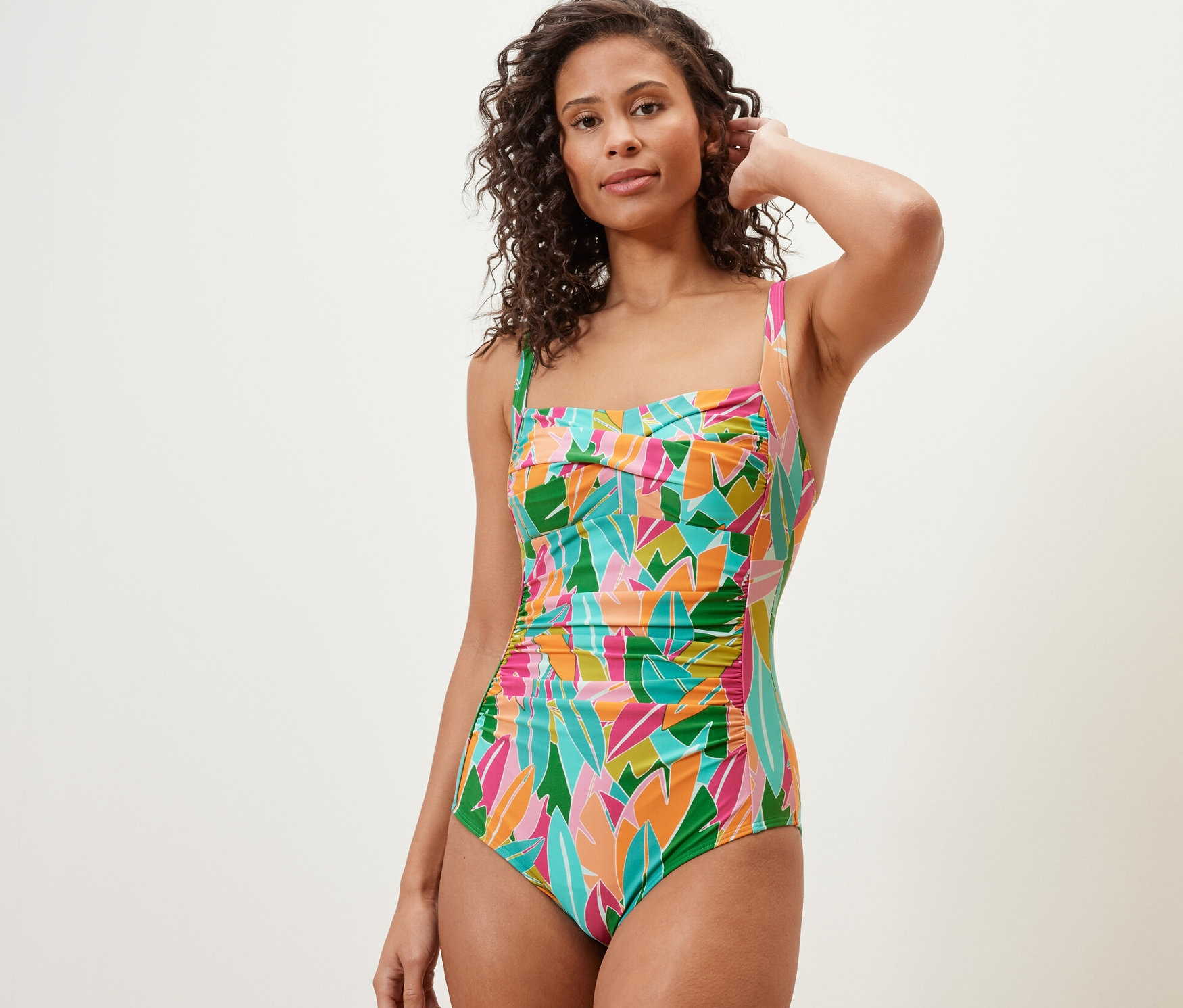 Žena pózuje v tvarujících plavkách různých barev.