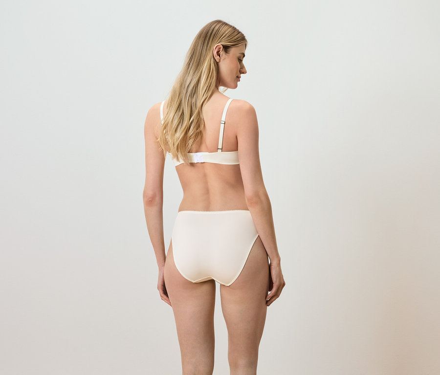 Zezadu je vidět žena s blond vlasy v béžové podprsence a kalhotkách.