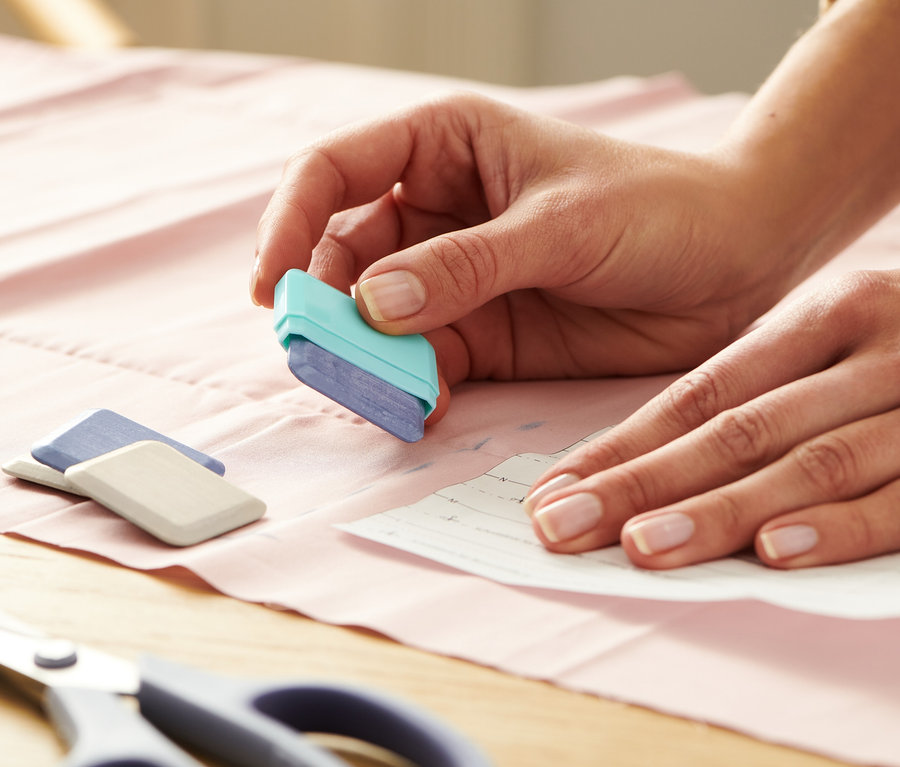 Žena obtahuje střih krejčovskou křídou.