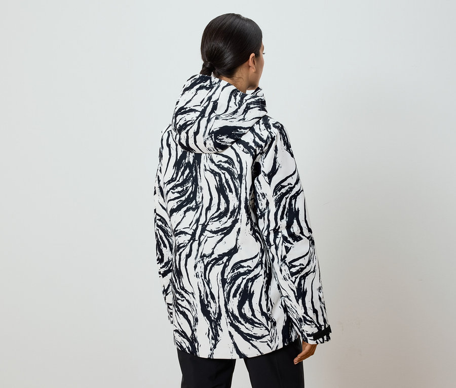 Zezadu je vidět žena s culíkem v černo-bílé bundě se vzorem a kapucí.