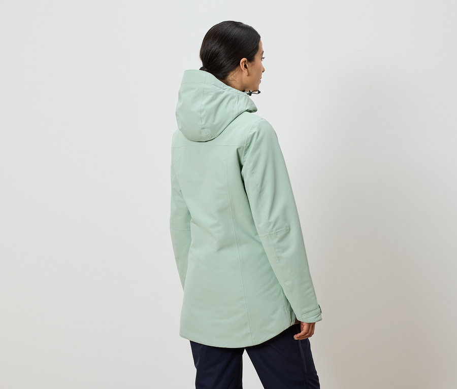 Zezadu je vidět žena v zelené bundě s kapucí a tmavě modrých kalhotách.