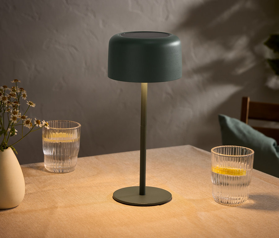 Stůl s vázou květin, dvě sklenice s citrony a zelená lampa.