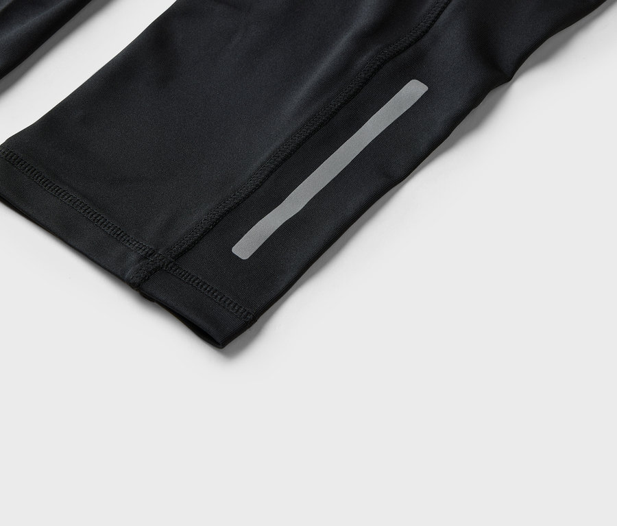 Detailní záběr na černé sportovní oblečení s reflexním pruhem.