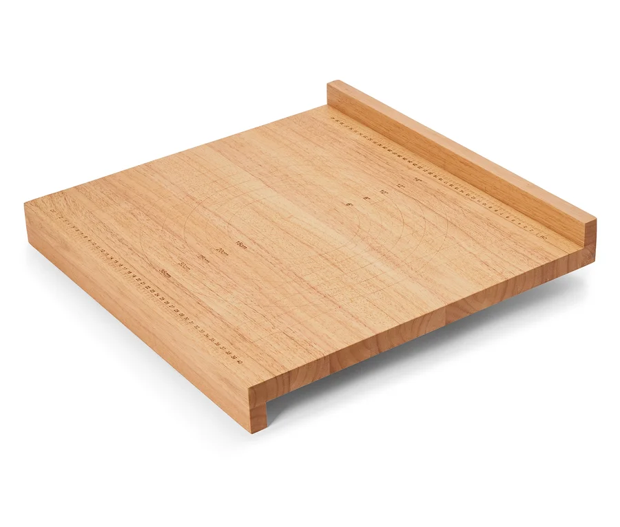 Čtvercové světle hnědé dřevěné prkénko s centimetrovými a palcovými značkami na povrchu.