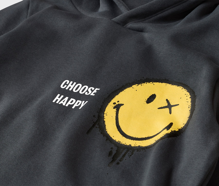 Tmavě šedá mikina s kapucí se žlutým smajlíkem a nápisem "CHOOSE HAPPY". Smajlík má jedno oko jako tečku a druhé jako křížek, působí jako nastříkaný.
