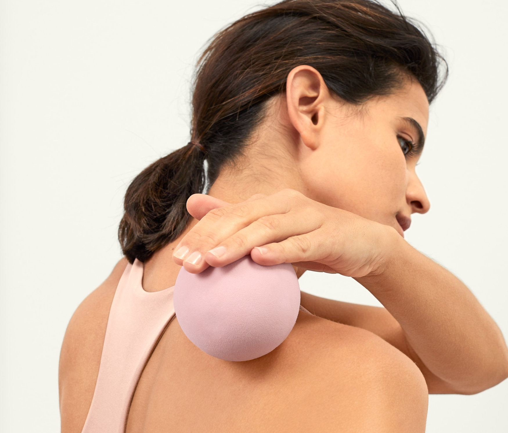 Žena si masíruje horní část zad masážním míčkem na uvolnění fascií.