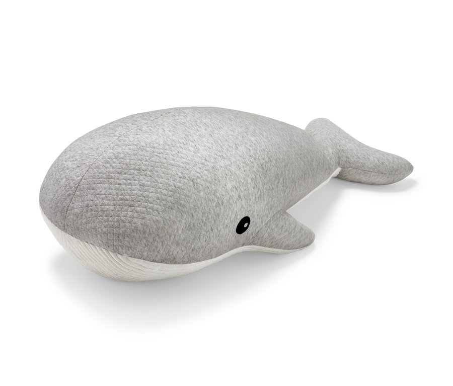 Šedá plyšová velryba leží na bílém pozadí. 