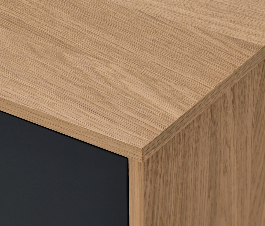 Detail rohu komody Bekeson v antracitové barvě s dřevěnou deskou.