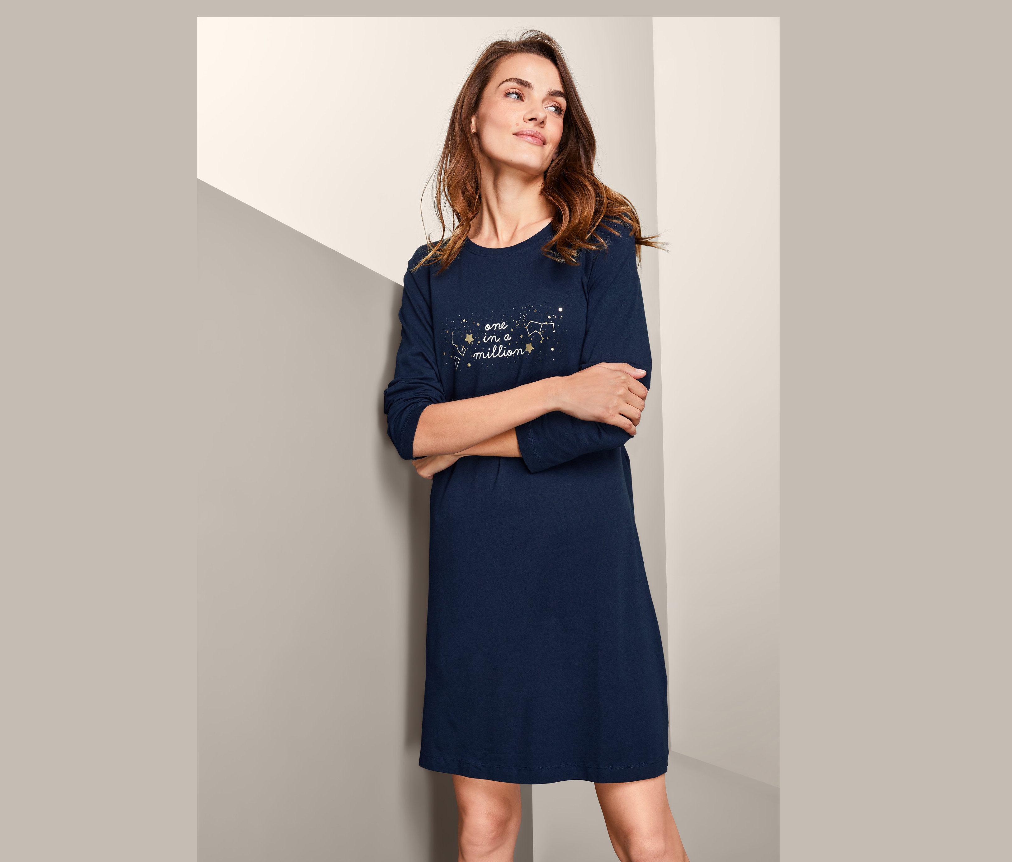 Žena má na sobě noční košili s dlouhým rukávem a potiskem souhvězdí.